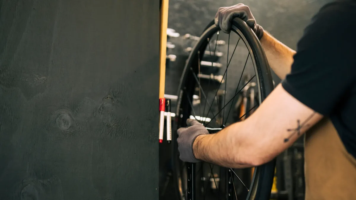 Persoon die aan het sleutelen is bij het achterwiel van een fiets. Persoon is een onderhoudsbeurt aan het uitvoeren in een fietsenwinkel in Oldenzaal.
