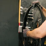 Persoon die aan het sleutelen is bij het achterwiel van een fiets. Persoon is een onderhoudsbeurt aan het uitvoeren in een fietsenwinkel in Oldenzaal.