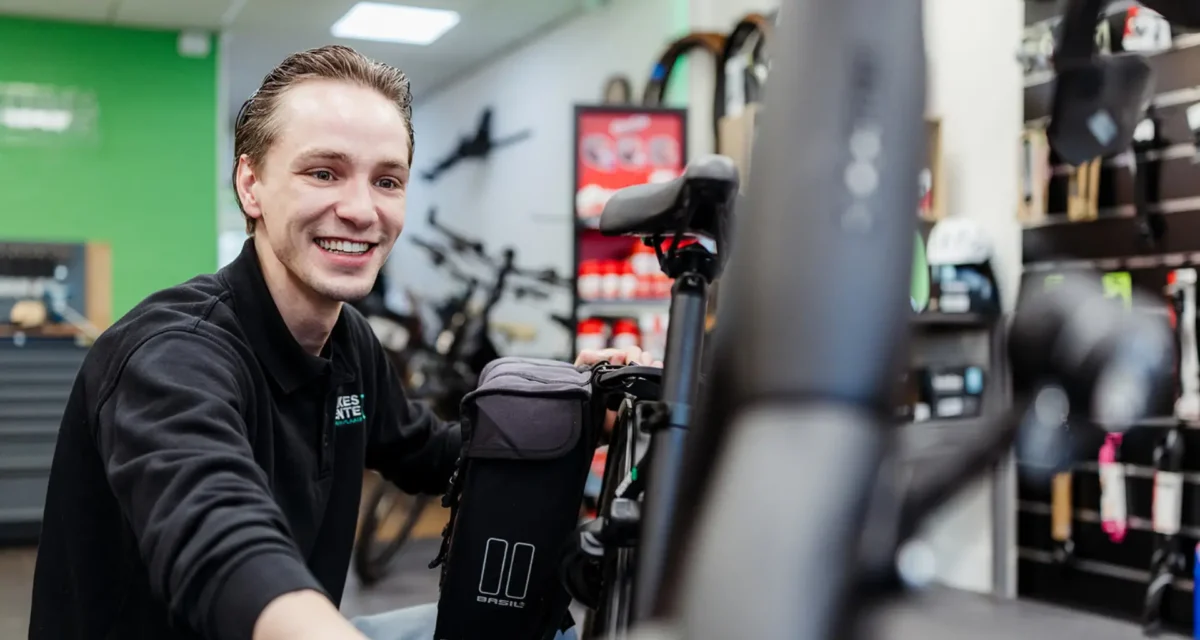 Service met een lach. Luuk Segerink, eigenaar van de fietsenwinkel in Oldenzaal Topbikes Twente, die een klant helpt met een lach op het gezicht.