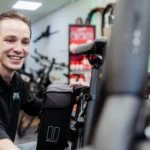 Service met een lach. Luuk Segerink, eigenaar van de fietsenwinkel in Oldenzaal Topbikes Twente, die een klant helpt met een lach op het gezicht.