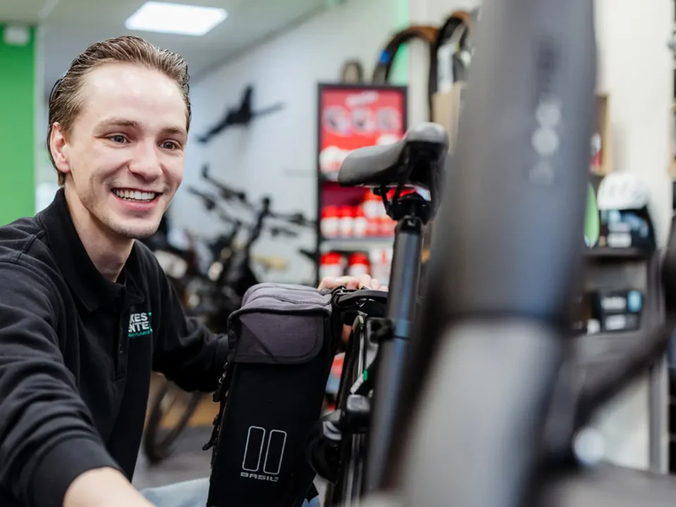Service met een lach. Luuk Segerink, eigenaar van de fietsenwinkel in Oldenzaal Topbikes Twente, die een klant helpt met een lach op het gezicht.