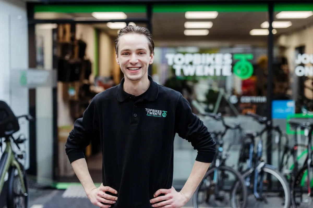 Luuk Segerink, eigenaar Topbikes Twente, die voor de fietsenwinkel in Oldenzaal staat met een glimlach.