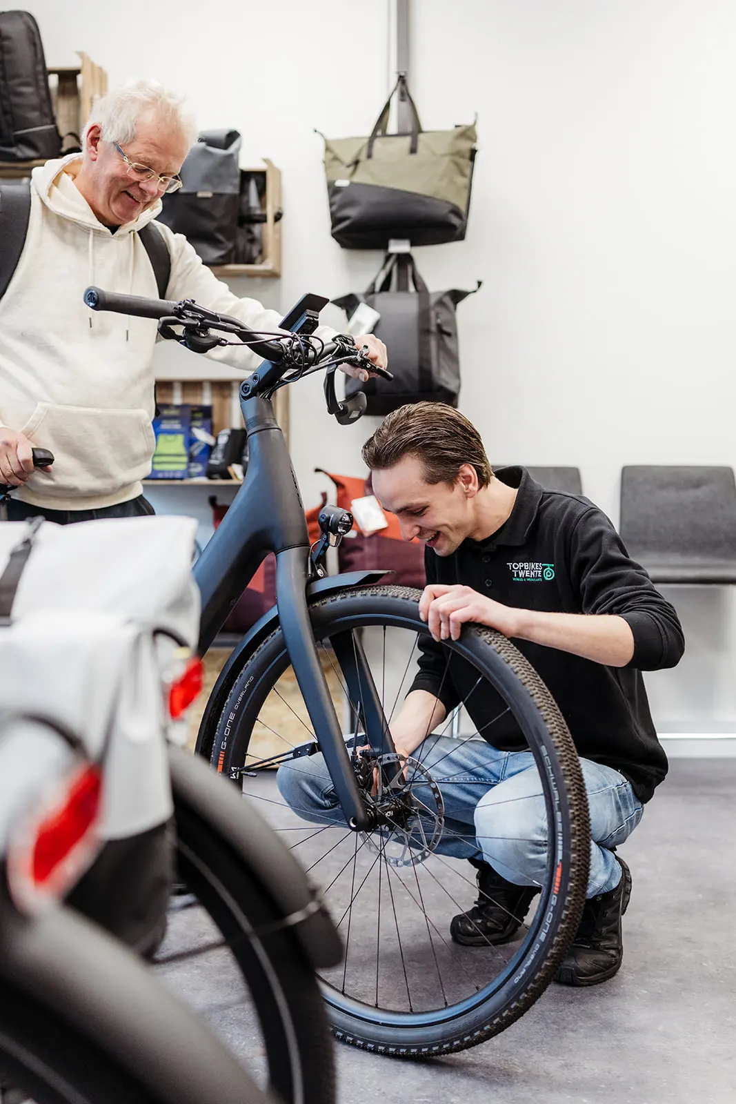 Klant van de fietsenwinkel in Oldenzaal, Topbikes Twente, die zijn laatste check op zijn fiets ontvangt. Altijd met een glimlach.