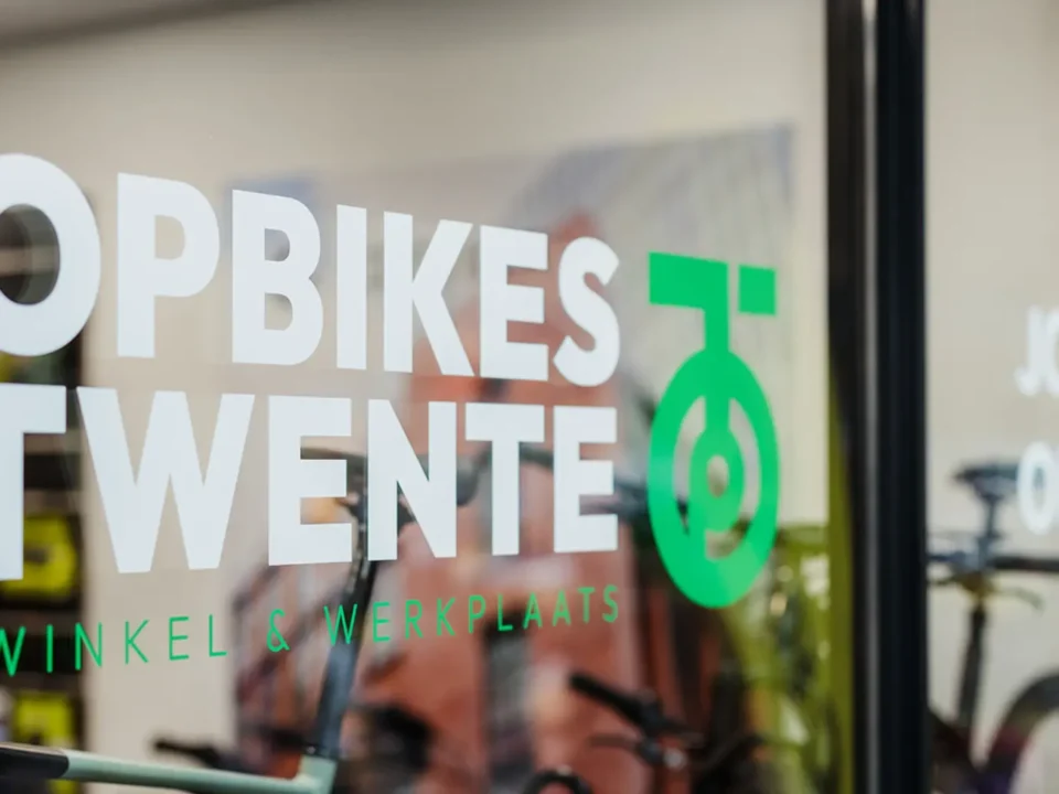 Voorkant van het raam bij Topbikes Twente, fietsenwinkel in Oldenzaal. Op het raam staat een sticker met logo van Topbikes Twente.